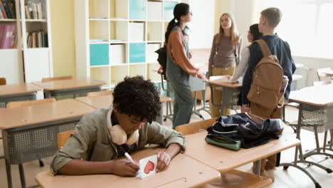 teenagers in a classroom setting, with one student drawing