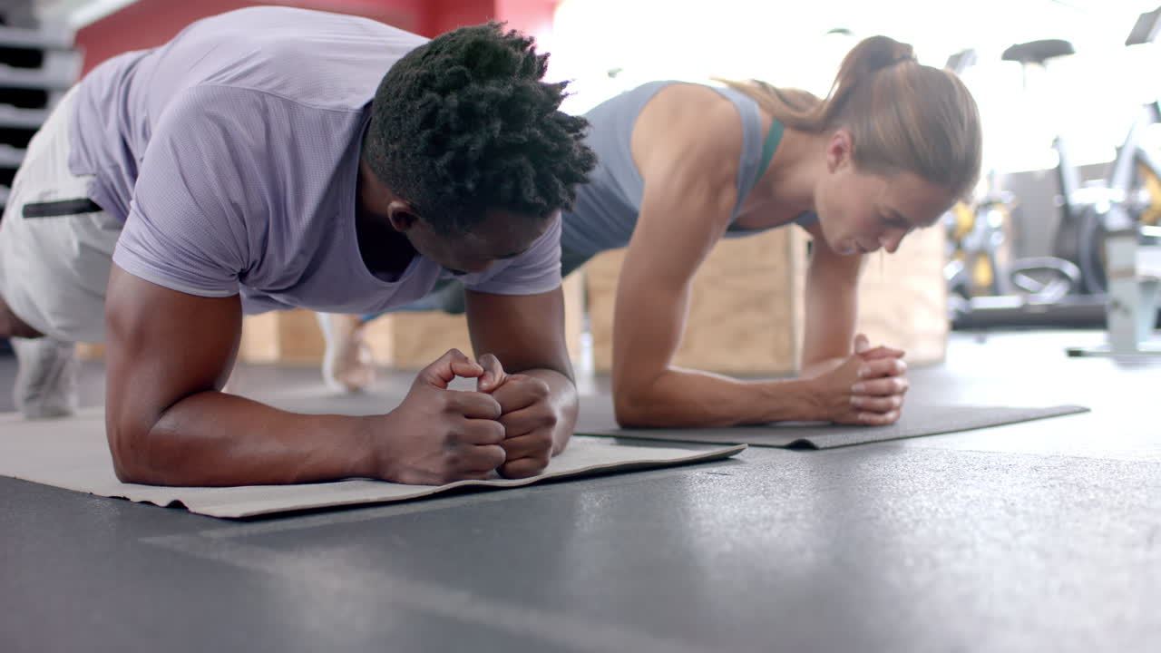 hombre afroamericano en forma y joven mujer caucásica haciendo ejercicio en el gimnasio