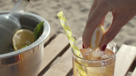 close up of a lemon being squeezed into drink with straw in slow motion, sunny day, slowmo