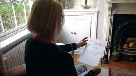 an unrecognizable senior woman worried about debts opening a debt letter