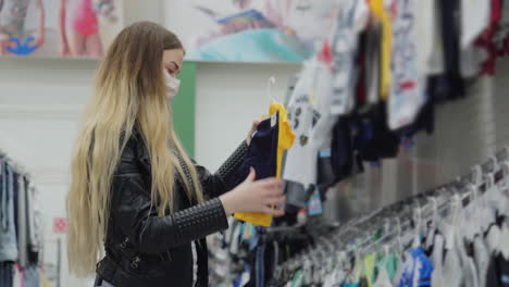 mujer comprando ropa para niños en una tienda con una máscara