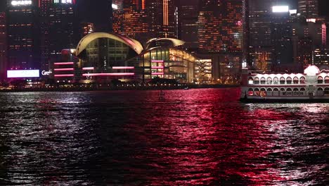 ferry moves across hong kong's illuminated harbor