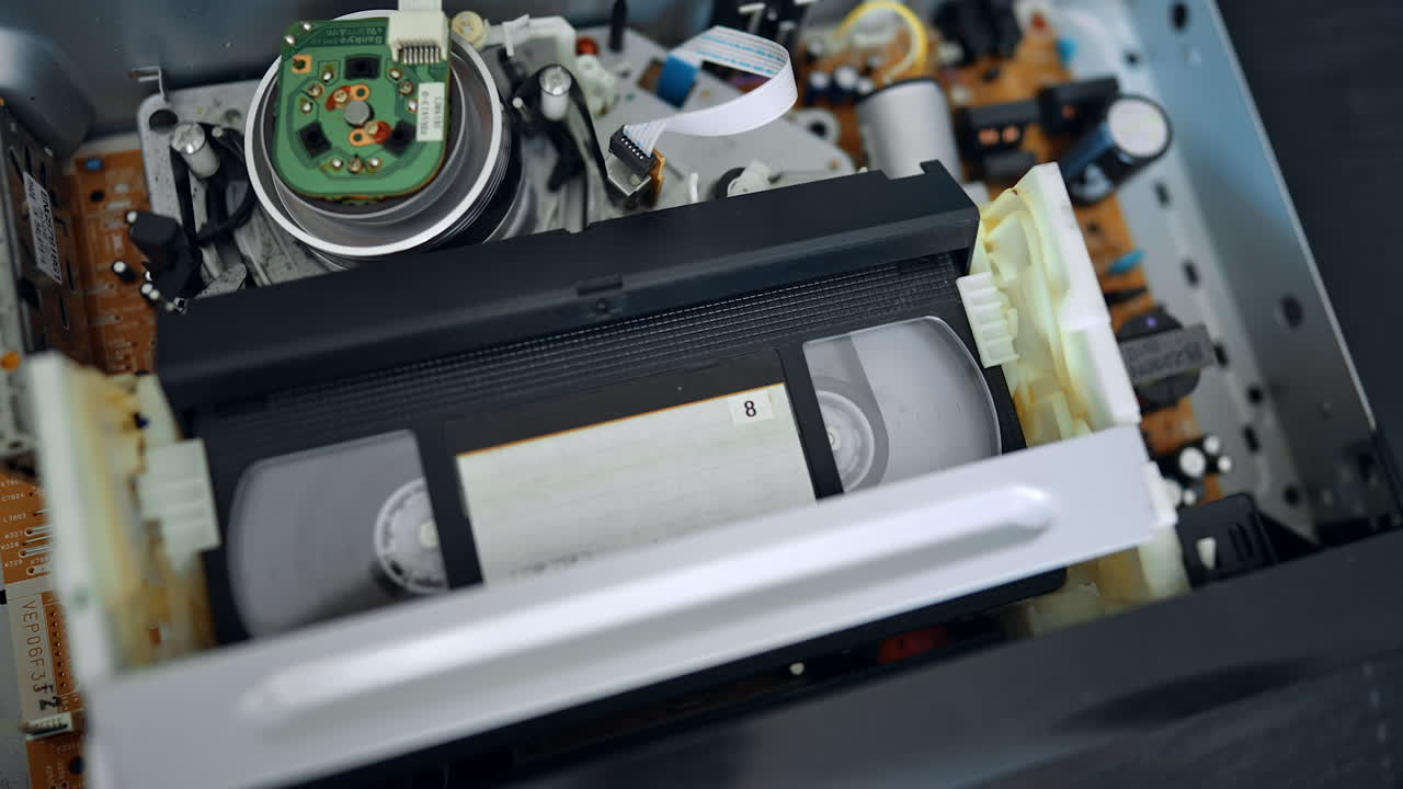 VHS cassette recorder inside the player. Close up. Finger presses the button and cassette pops out