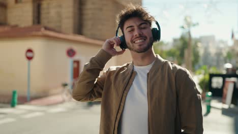 young hispanic man smiling confident listening to music at street