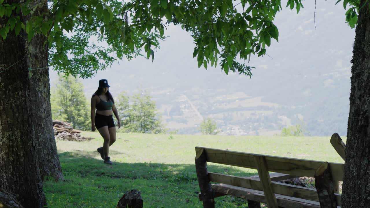 Handheld of man and woman exploring valley surrounded by trees, mountains in background, near Laguna Corazon in Liquiñe, Chile