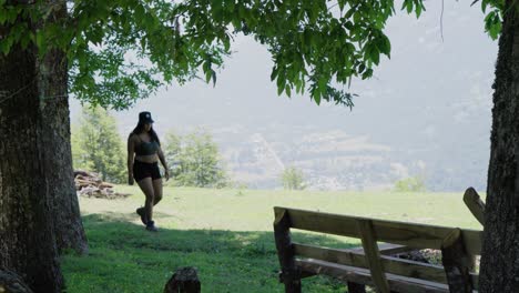 handheld of man and woman exploring valley surrounded by trees, mountains in background, near laguna corazon in liquiñe, chile