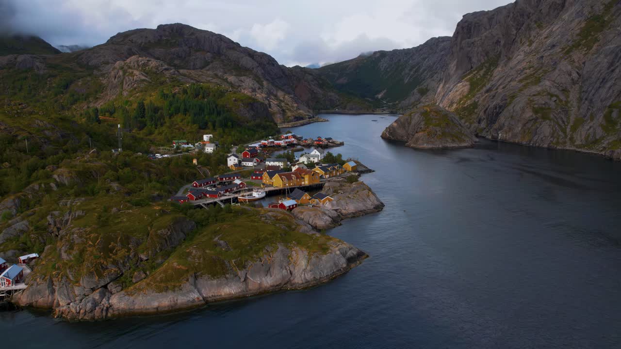 Time-lapse of traditional wooden red and yellow cabin village on Lofoten Islands with a boat passing by.