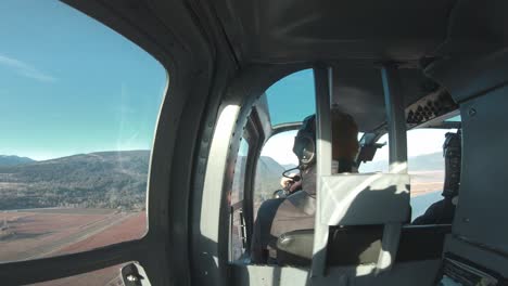 backseat of a helicopter looking at a photographer take photos of a winter canadian landscape