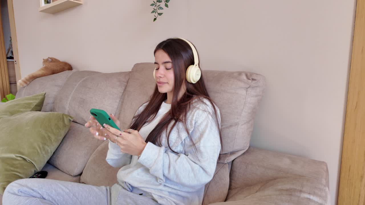 mujer relajándose en el sofá con auriculares y teléfono
