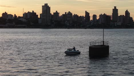 fishing boat floats on parana river at sunset with posadas skyline in background