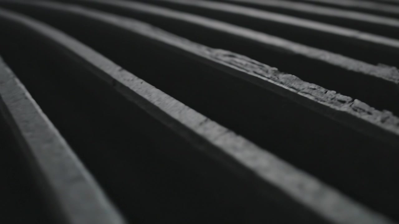Pulling focus, camera revealing ribbed slatted surface in studio, to reveal chips and dark gaps