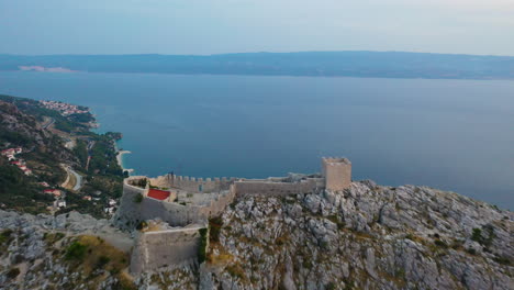 Erstaunliche-Festung-Omis-Starigrad-Auf-Der-Bergspitze-Bei-Sonnenuntergang,-Kroatien,-Luftbild