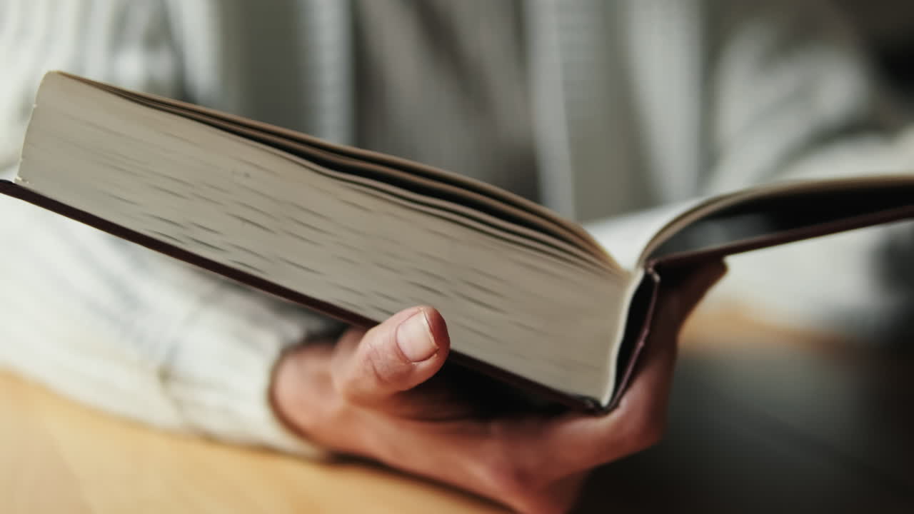 Close-up of Person's Hand Turning Page of an Open Book