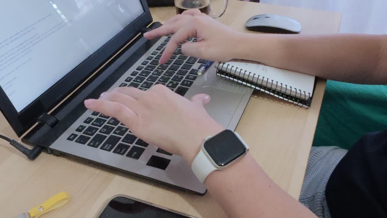 A person is using a laptop and a cell phone. The laptop is open and the cell phone is in their hand.