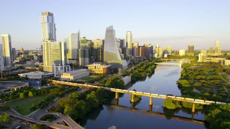 Aerial-view-of-a-train-and-the-sunlit-Austin-cityscape,-in-USA---approaching,-drone-shot