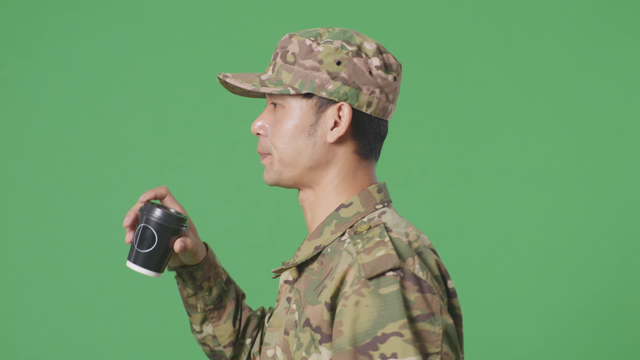 녹색 스크린 배경 스튜디오에서 고 커피를 마시는 아시아인 군인의 클로즈업