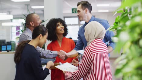 group of diverse business people shaking hands and talking in office, slow motion