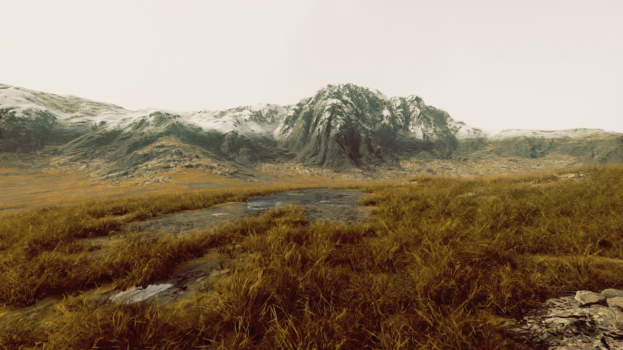 Vast mountain landscape with snow capped peaks under a cloudy sky