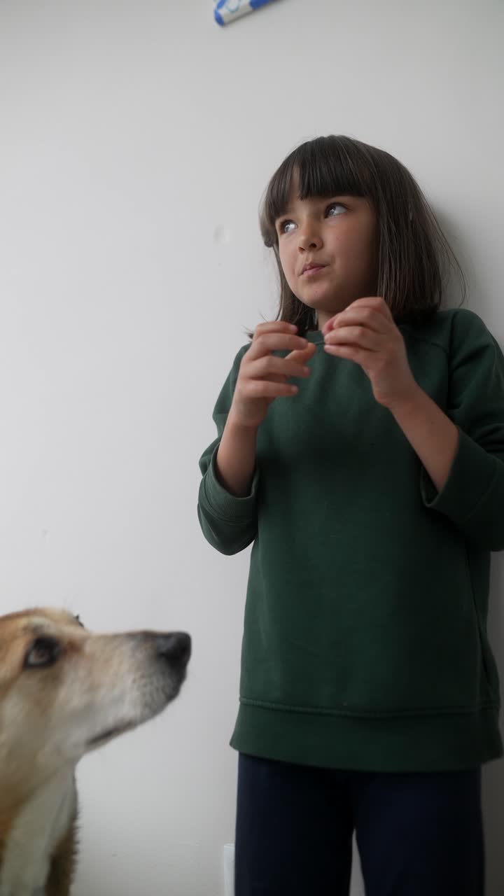 Girl playing with a small object in front of a dog