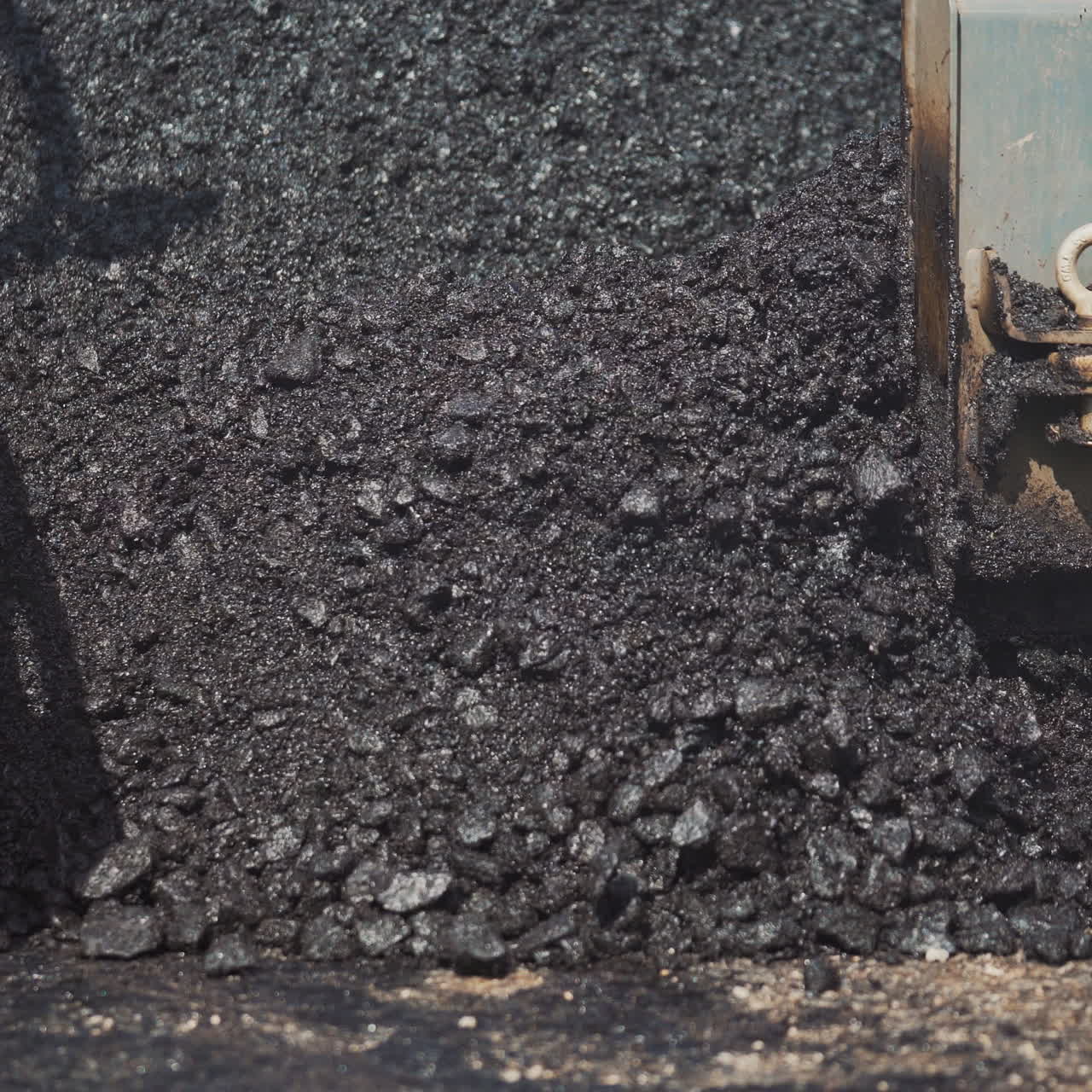 Truck machine for paving apply asphalt to the road. Spillage of asphalt on the street. Pouring blacktopping in a sunny day. Road work, street repair. Close-up. Slow motion.