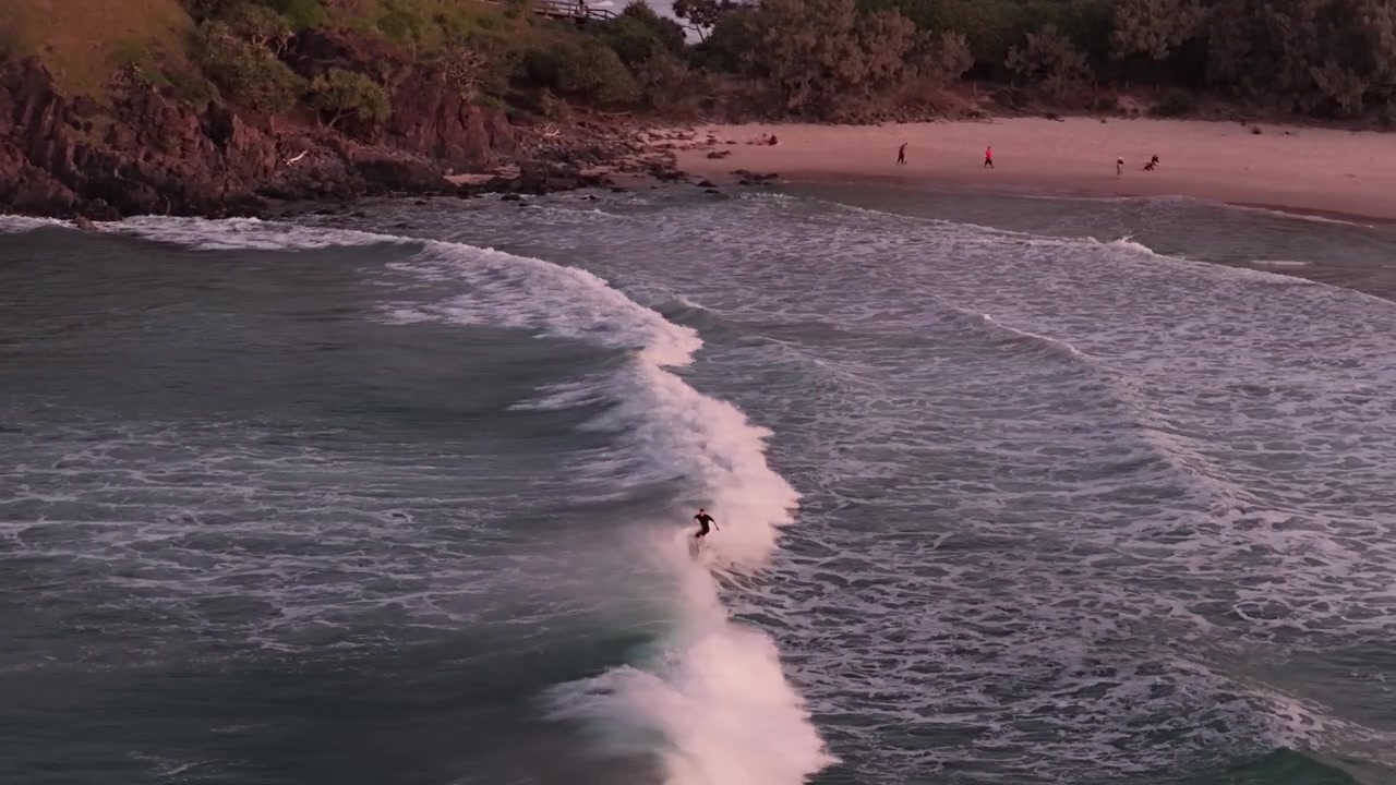 Surfare som rider på havsvågor vid Cabarita Beach i NSW, Australien vid solnedgången - Drönarbild