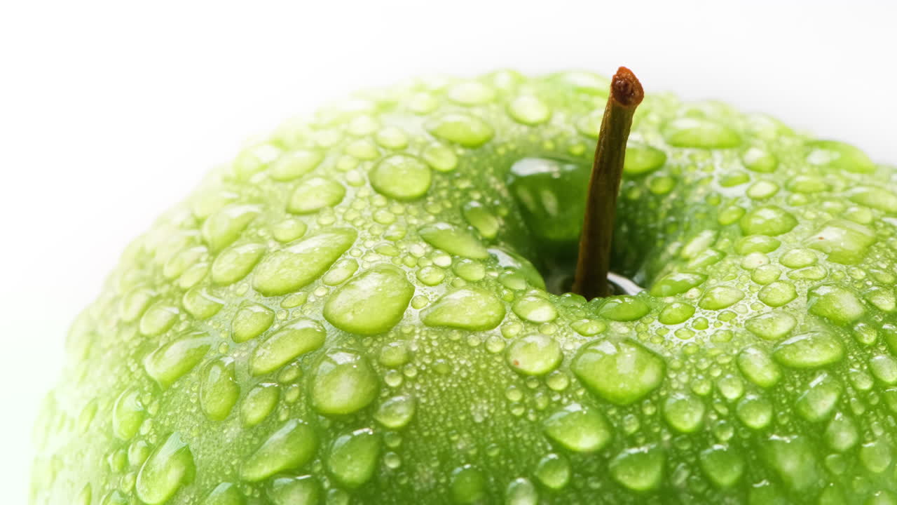 Primo piano di una deliziosa mela verde fresca e croccante con goccioline d'acqua.