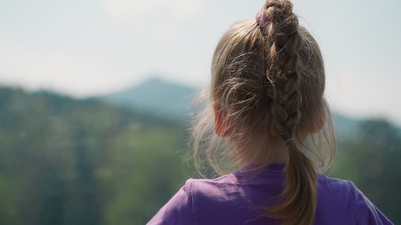 작은 아이가 케이블 웨이 오두막에서 산 정상을 바라보고 있습니다.