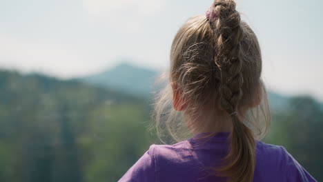 little child looks at mountain peak from cable way cabin