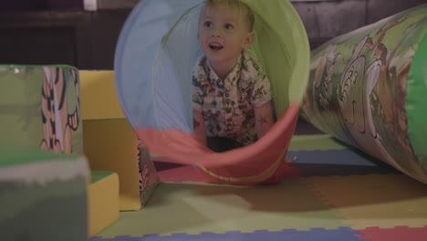 young happy child having an amazing time crawling through a soft play tunnel - ungraded