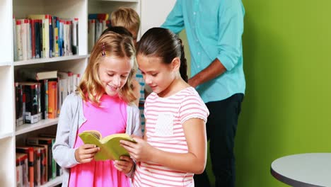 Profesor-Y-Niños-Leyendo-Un-Libro-En-La-Biblioteca.