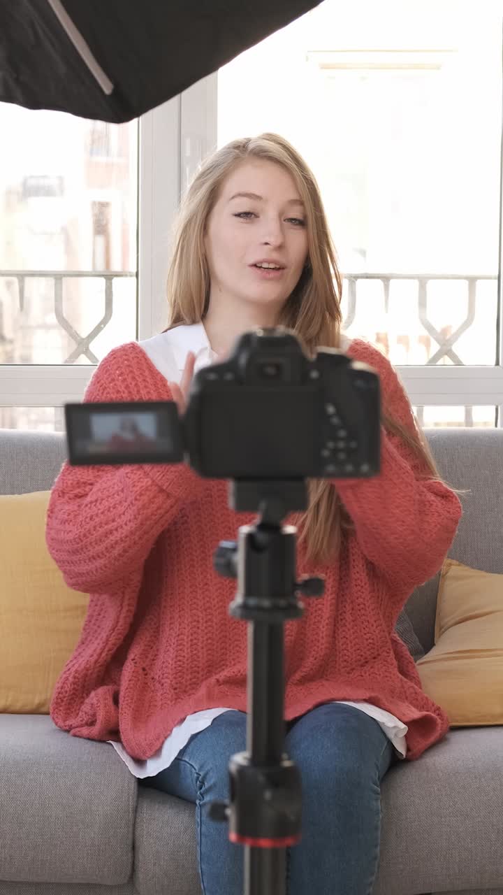 Young woman talking on mobile camera, explaining a photo camera. Content creator concept