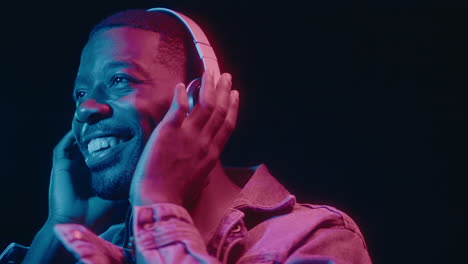 smiling black man in headphones dancing in neon light