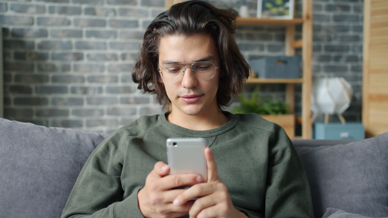 Giovane uomo che usa lo smartphone sul divano