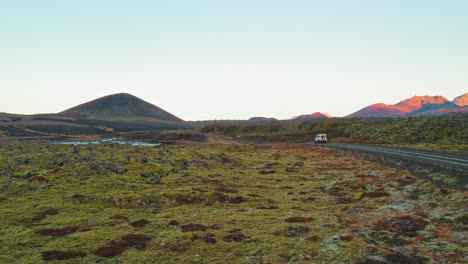 aerial drone shot of white land rover defender driving through colorful volcanic landscape in iceland