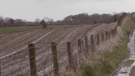 Farmland-fence-on-country-lane-over-rolling-hills,-overcast-still-shot