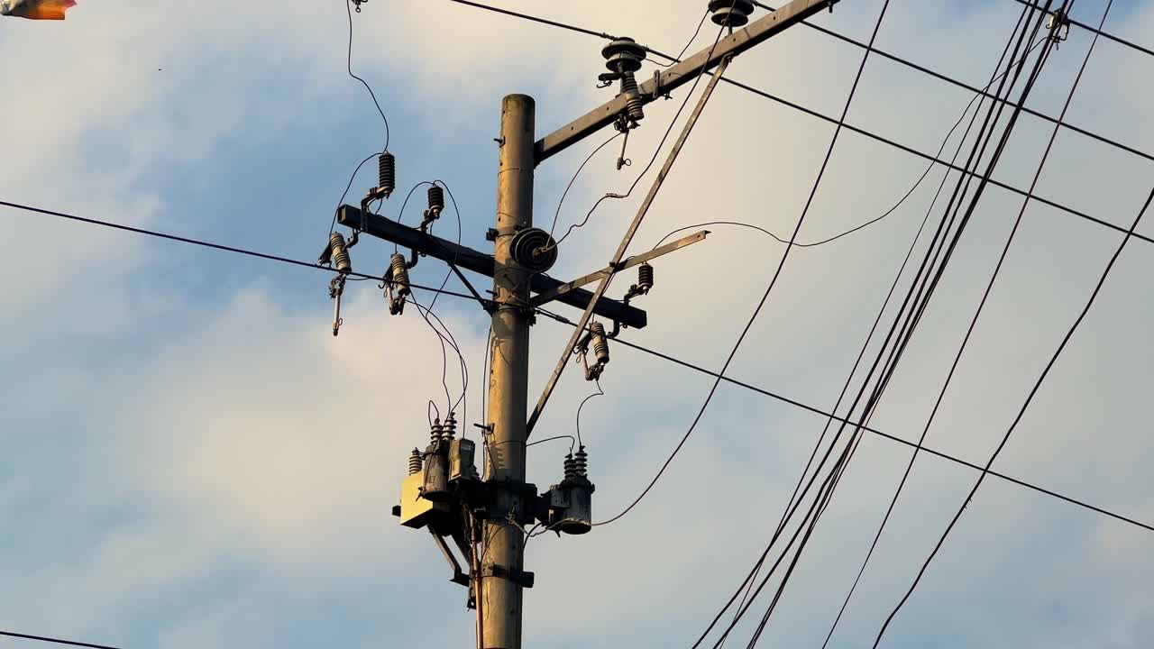 Close-up of an electric utility pole with multiple power lines and transformers set against a blue sky, perfect for energy, infrastructure, and technology projects