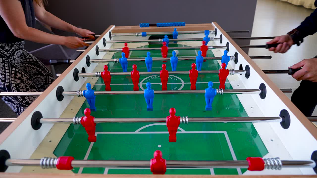 el video muestra a dos personas, un hombre y una mujer, jugando al fútbol de mesa o al futbolín en un espacio de oficina durante un descanso en 4k estonia tallinn europa