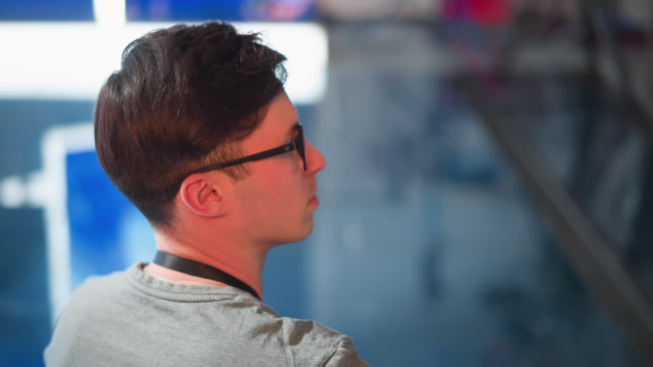 Person in TV studio adjusting video equipment, focused on control panel and monitor. Seen from behind, studio lighting and broadcast setup visible in background