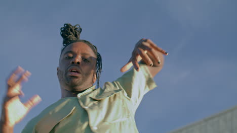 Modern-dancer-looking-camera-sky-background.-African-american-guy-moving-hands