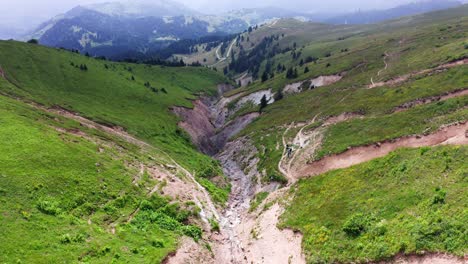 mountain landscape of canyon between slanted green hills, descending drone flight