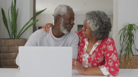 una pareja de ancianos afroamericanos pasando tiempo juntos en casa usando una computadora portátil en distanciamiento social
