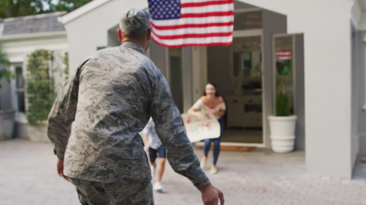 soldado masculino caucásico saludando a un hijo y una esposa felices con un cartel de bienvenida fuera de su casa