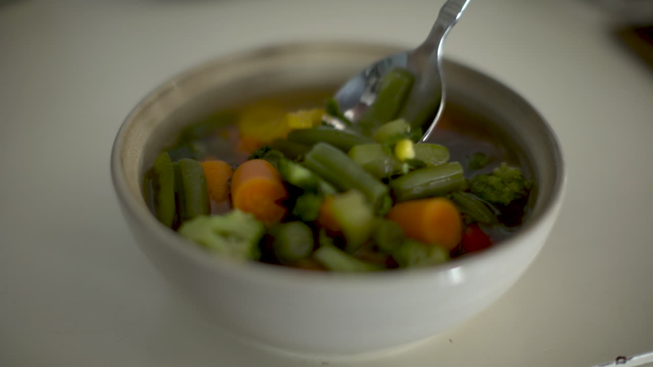 disparo estático de sopa de verduras que se agita casualmente en un cuenco beige