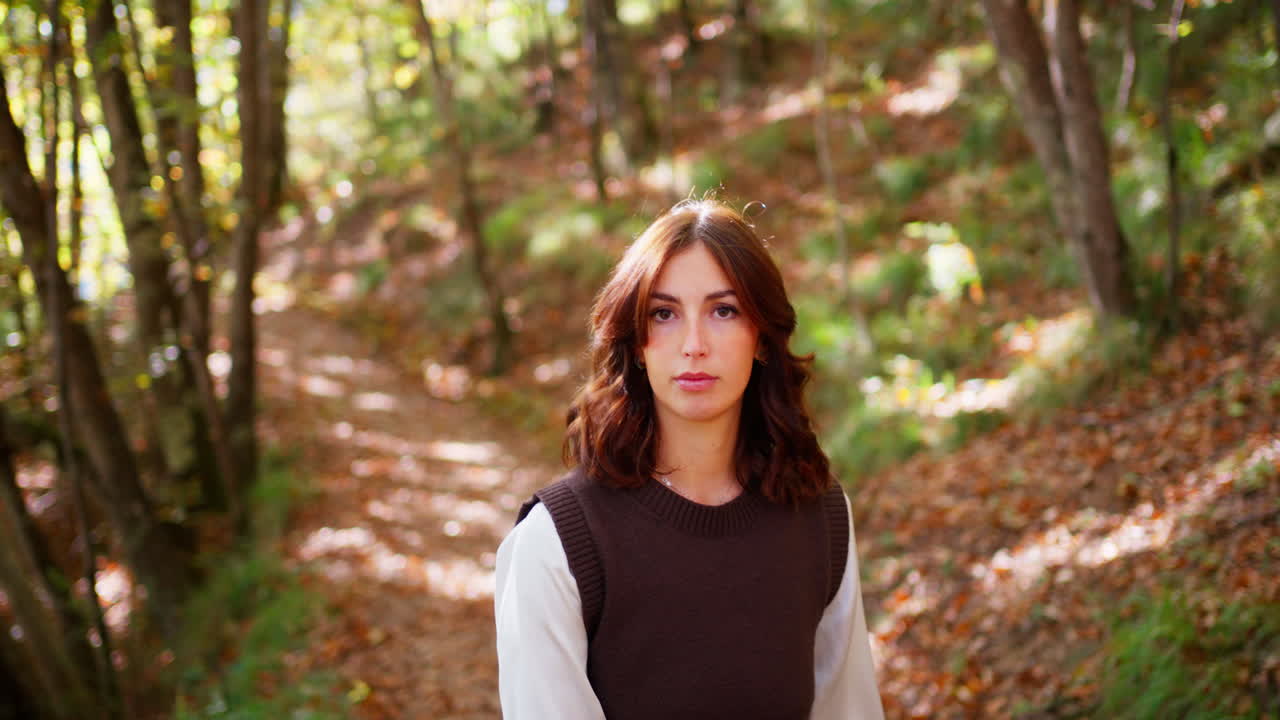 Young woman poses gracefully in a sunlit autumn forest path