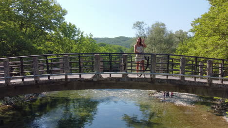 una mujer está posando en el puente de aristi, disfrutando de la vista panorámica de la belleza natural que rodea el famoso río voidomatis a medida que fluye a través del parque nacional de vikos en epirus, grecia, europa