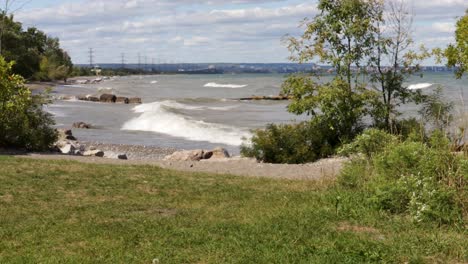 waves gently crashing along a rocky shoreline overlooking burlington, ontario, from right to left