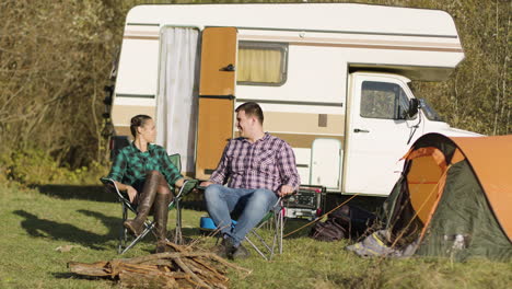 hipster couple sitting on their camping seats and holding hands