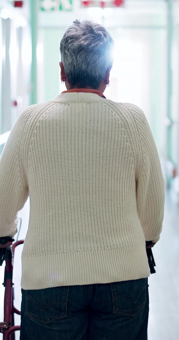 Senior Woman Walking Down Hospital Hallway with Mobility Aid