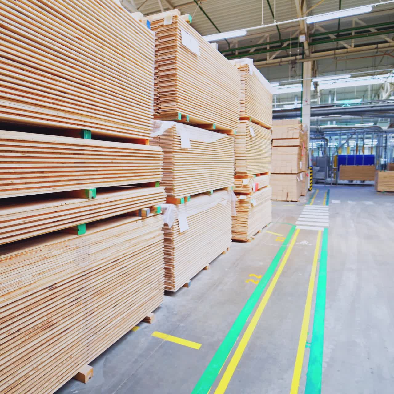 Large warehouse of timber materials. Motion camera inside the warehouse. Neatly stacked wooden boards for floor production in a warehouse.