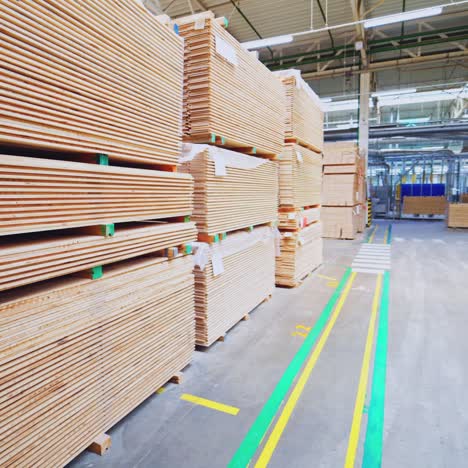 large warehouse of timber materials. motion camera inside the warehouse. neatly stacked wooden boards for floor production in a warehouse.